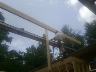 Carpenter setting a ridge beam over a new addition frame — Ice Dam Removal by Roofing Brothers in Manteo
