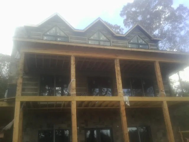 Dormers and porch framing on a large log home under construction — Roof Coating work by our crew in Manteo