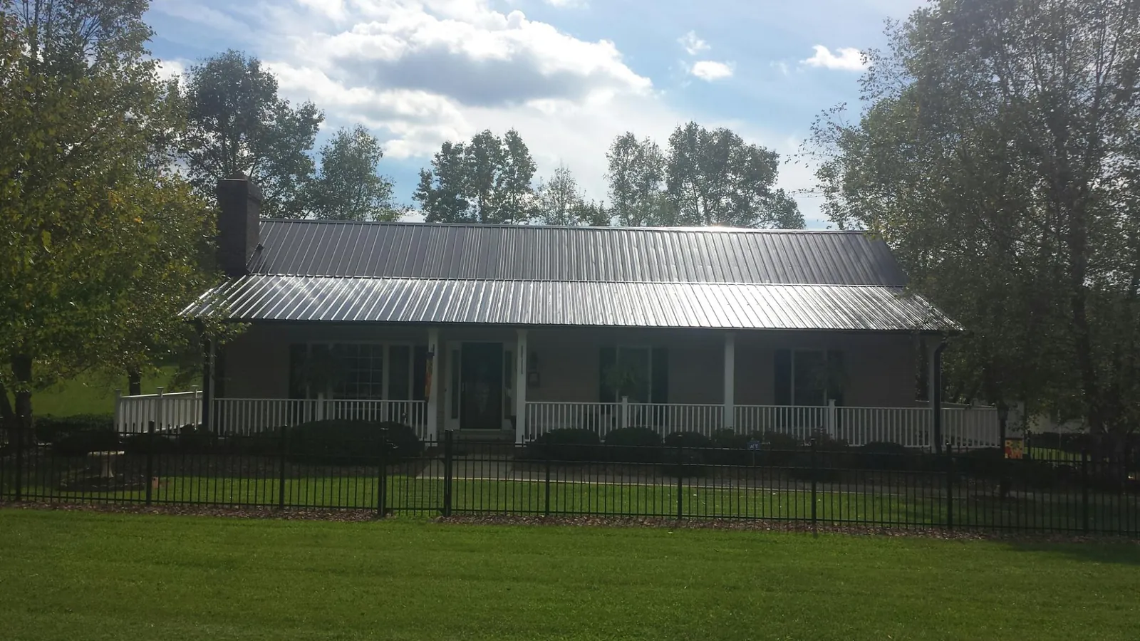 Gray metal roof on a brick ranch with a full width front porch — Gutter Guard Installation work by our crew in Manteo