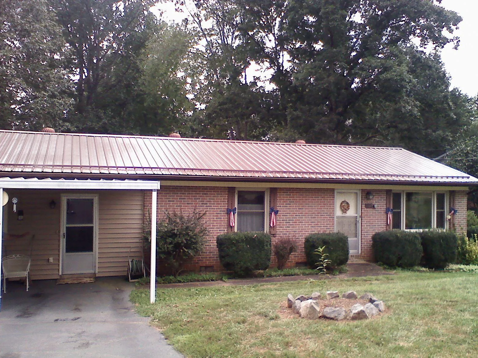 Bronze metal roof and carport on a brick ranch home — Roof Repair work by our crew in Manteo