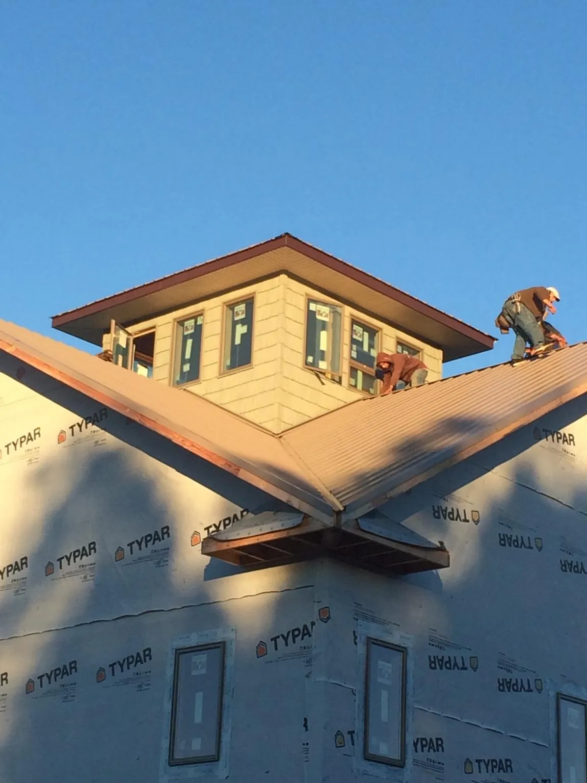Roofers working around a rooftop cupola on a new metal roof at sunset — Roof Waterproofing in Manteo by Roofing Brothers